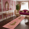 A long pink runner rug with a gold leopard print design on a dark wood floor in an elegant room.