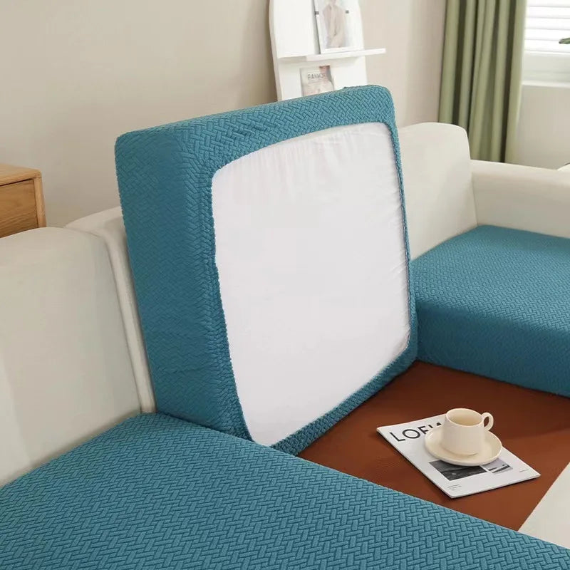 A teal woven cushion cover for a sofa seat protector placed on a brown tray.
