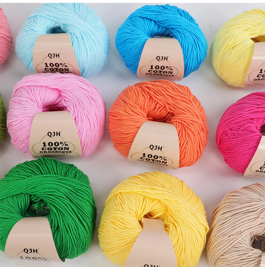 A collection of brightly colored 100% organic cotton yarn skeins in various shades including blue, pink, orange, yellow, and 
