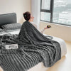 A person is wrapped in a thick gray ultra-soft plush winter blanket indoors near a window.