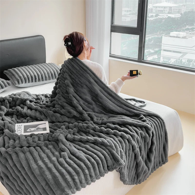 A person is wrapped in a thick gray ultra-soft plush winter blanket indoors near a window.