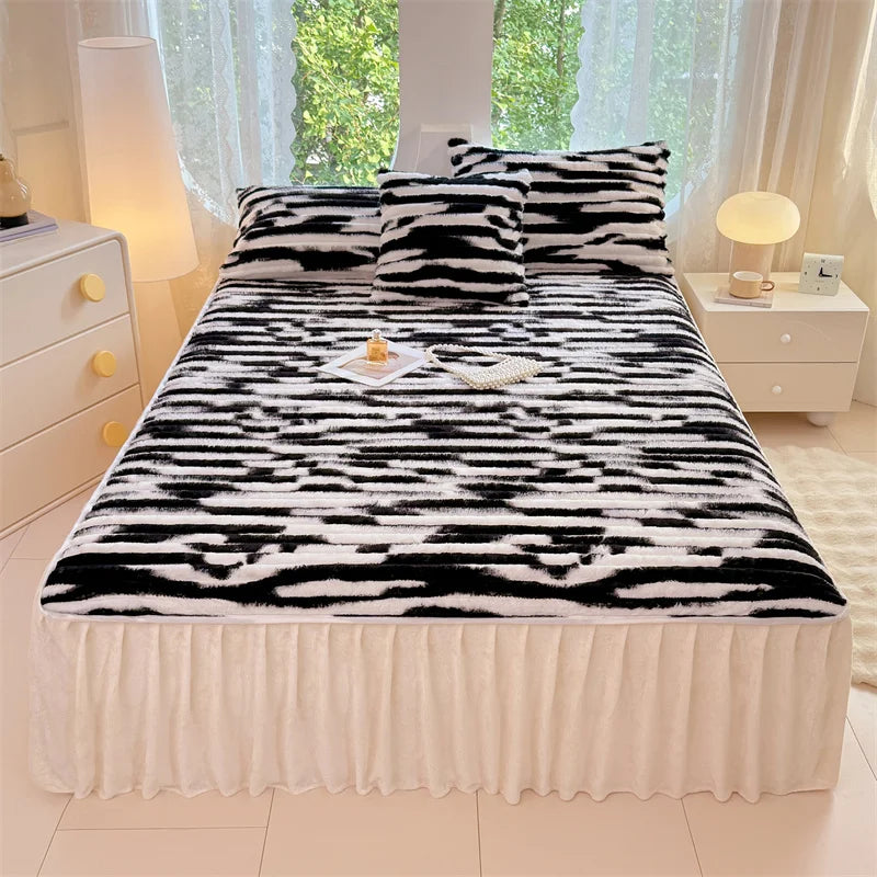 A black and white zebra print duvet cover with a sheer white bed skirt and decorative pillows.