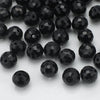 A close-up view of small, shiny black faceted glass beads for jewelry making.
