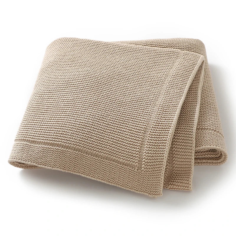A beige knitted baby swaddle blanket folded and displayed on a white background.