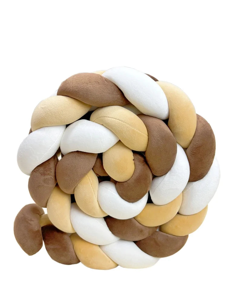 A round, handmade knotted floor mat for bed decor made of various shades of tan and cream fabric.