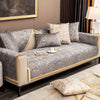 A luxurious gray velvet sofa with gold trim and patterned cushions on a modern living room sofa.