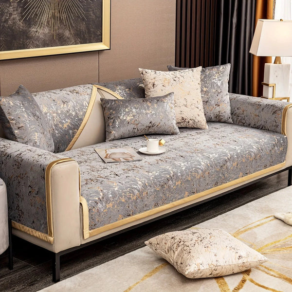 A luxurious gray velvet sofa with gold trim and patterned cushions on a modern living room sofa.