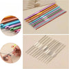 A collection of various colored crochet needles and stitch markers arranged diagonally on a light background.