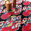 A close-up of a black fabric with a vibrant floral pattern in red, orange, gray, and white, displayed next to brass cylindric