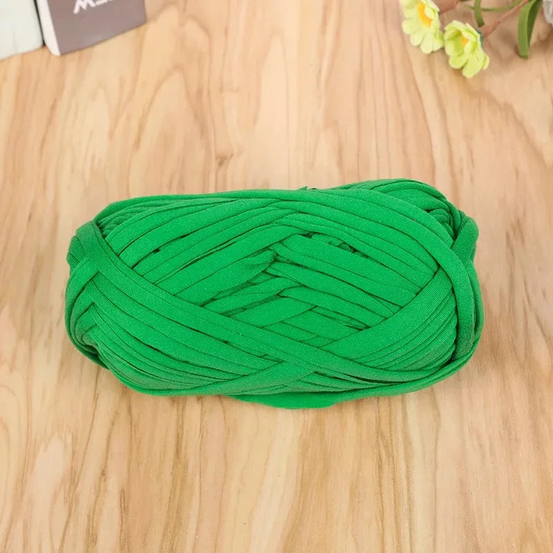 A ball of bright green thick polyester craft yarn for knitting and crochet lying on a wooden surface.