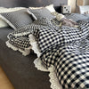 A plaid duvet cover and pillowcase set featuring black and white checkered fabric on a gray bed.