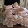 A pink ruffled duvet cover set with gathered fabric and decorative stitching displayed on a bed.
