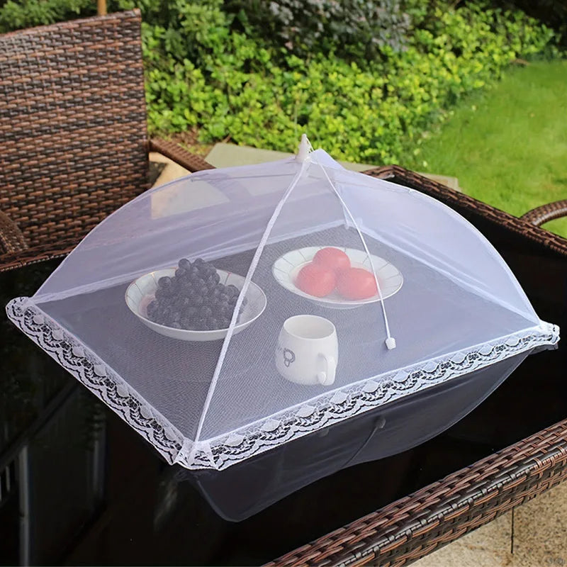 A clear mesh insect and fly protection cover is placed over a bowl of fruit on a dark wicker tray.