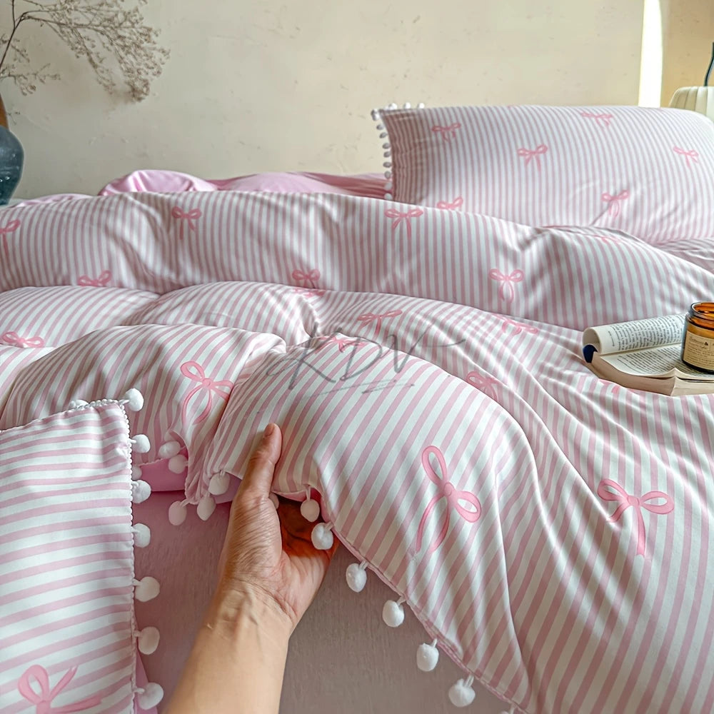 A pink and white striped quilt duvet set with matching pillowcases featuring a delicate pink bow print.
