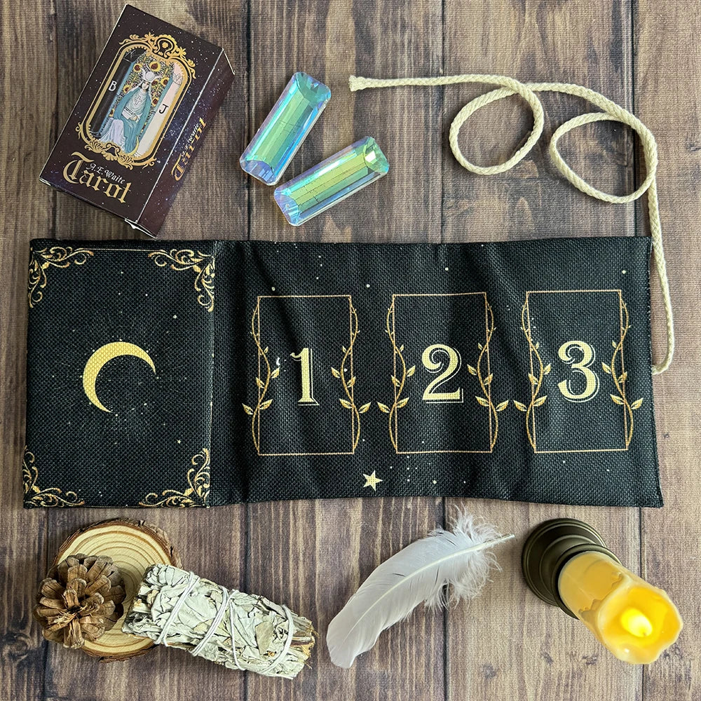 A black velvet pouch with gold detailing holds three tarot cards and a feather on a wooden surface.
