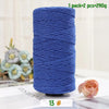 A spool of medium-thick blue yarn used for crafting, next to a pink rose flower.