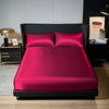 A vibrant magenta satin bedding set featuring a fitted sheet and two pillows displayed on a black bed frame.