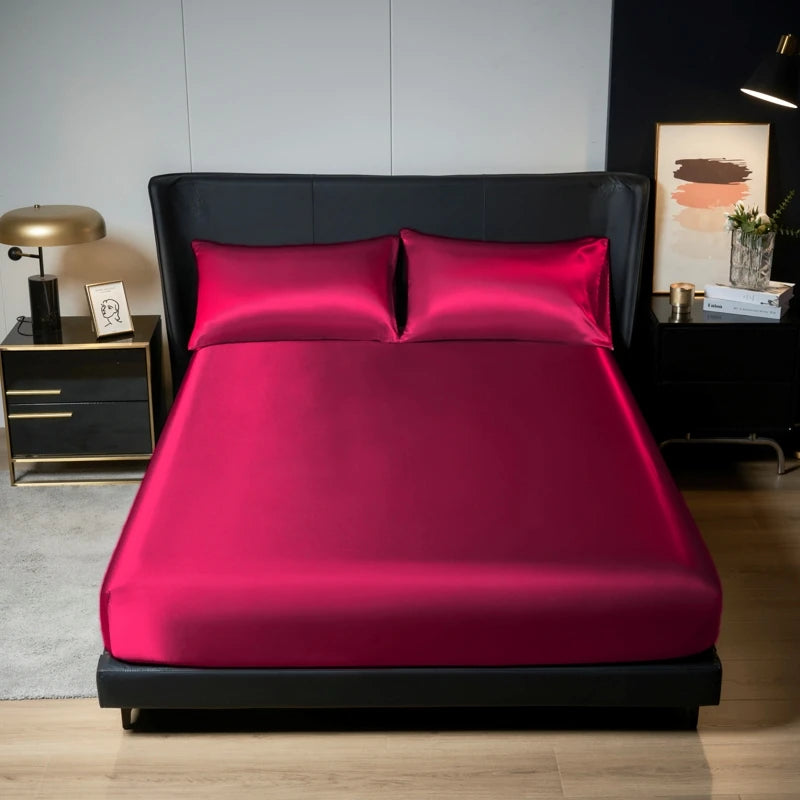 A vibrant magenta satin bedding set featuring a fitted sheet and two pillows displayed on a black bed frame.