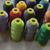A collection of spools of high tenacity polyester sewing thread in various colors including green, purple, orange, and blue.