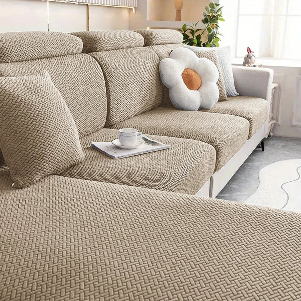 A beige thick jacquard sofa seat cushion cover with decorative pillows and a white flower accent on a light-colored sofa.