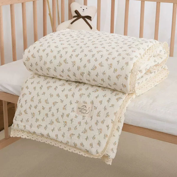 A cream colored muslin swaddle blanket folded on a wooden crib railing.