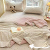 A light beige cartoon quilting comforter with pink accents and matching pillows on a bed.