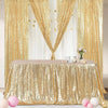 A gold sequin rectangle table cover draped with sheer gold curtains and decorated with pink flowers.