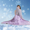 A woman is holding a purple quilted blanket in front of a snowy blue background.