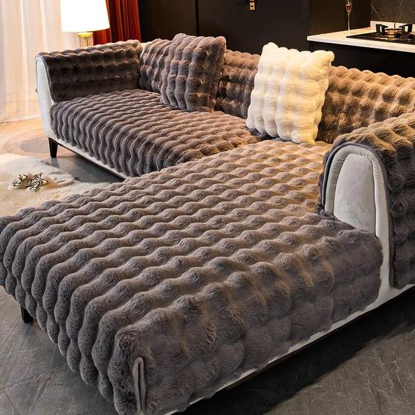 A plush velvet sofa cover in gray features tufted upholstery and a light cream cushion on a modern sofa.