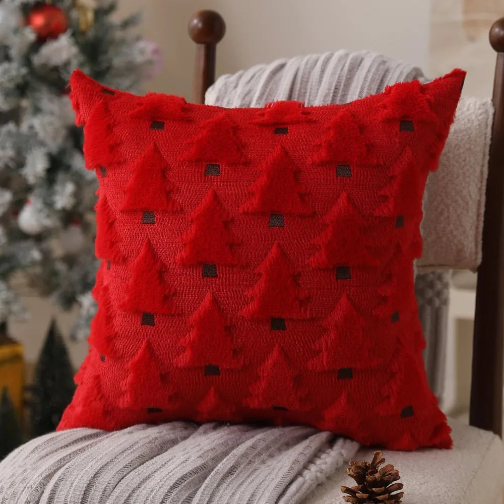 A red knitted throw pillow with a textured pattern resembling Christmas trees, resting on a gray blanket.