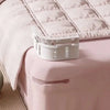 A white invisible bed sheet clip is resting on a pink quilted bed sheet.
