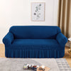 A deep blue stretch knit sofa cover featuring a bubble lattice texture displayed on a light rug.