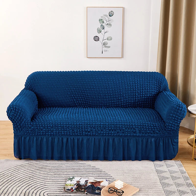 A deep blue stretch knit sofa cover featuring a bubble lattice texture displayed on a light rug.