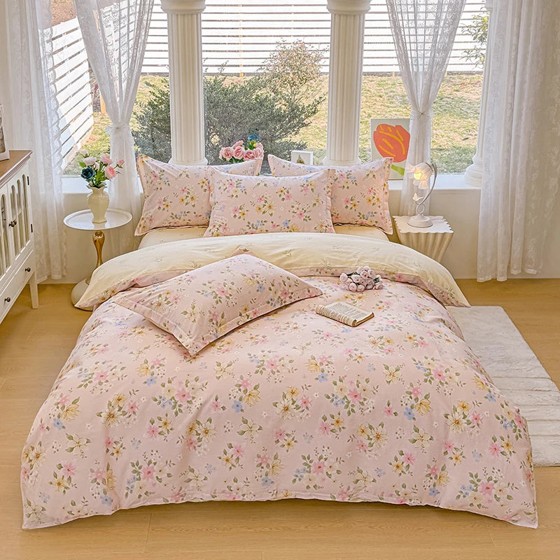 A pink floral duvet cover and pillow set displayed on a bed in a bright room with white curtains.