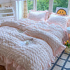 A pink lace seersucker duvet cover set displayed on a bed with white and pink decor.