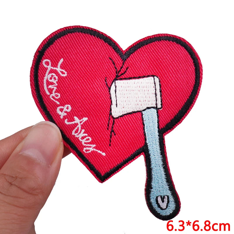 Red heart shaped embroidered patch featuring a white letter iron and a small black thread detail.