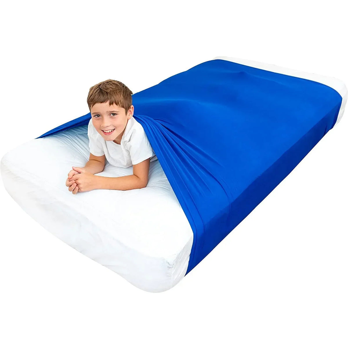 A young boy smiling while lying on a white bed sheet covered by a bright blue breathable stretchy sensory bed sheet.