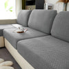 A close-up of a gray jacquard knit sofa cushion cover on a light-colored sofa.