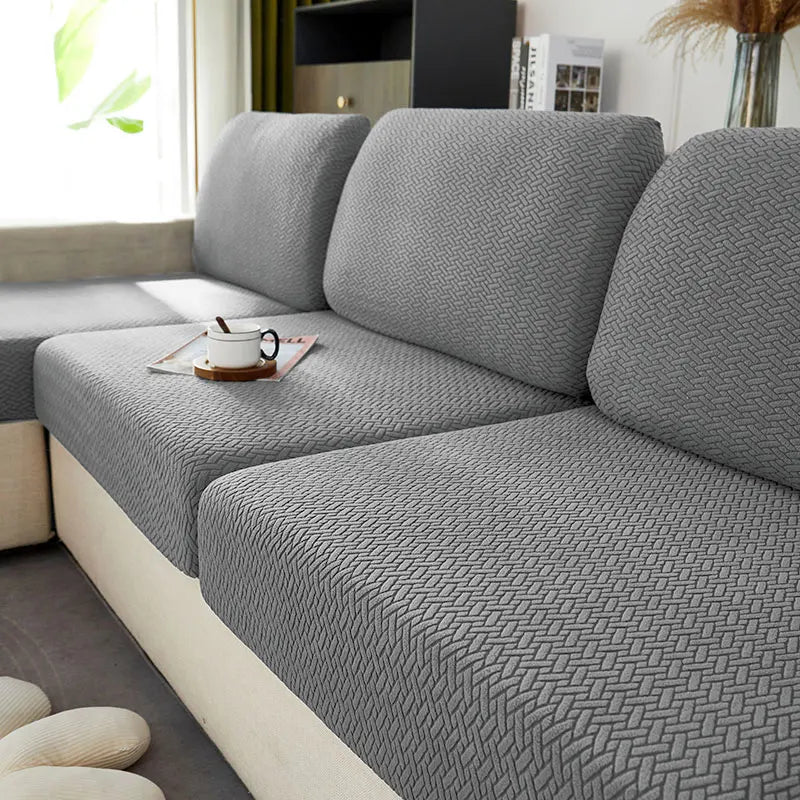A close-up of a gray jacquard knit sofa cushion cover on a light-colored sofa.