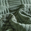 Close-up of olive green quilted fabric texture from a lightweight queen quilt bedding set.