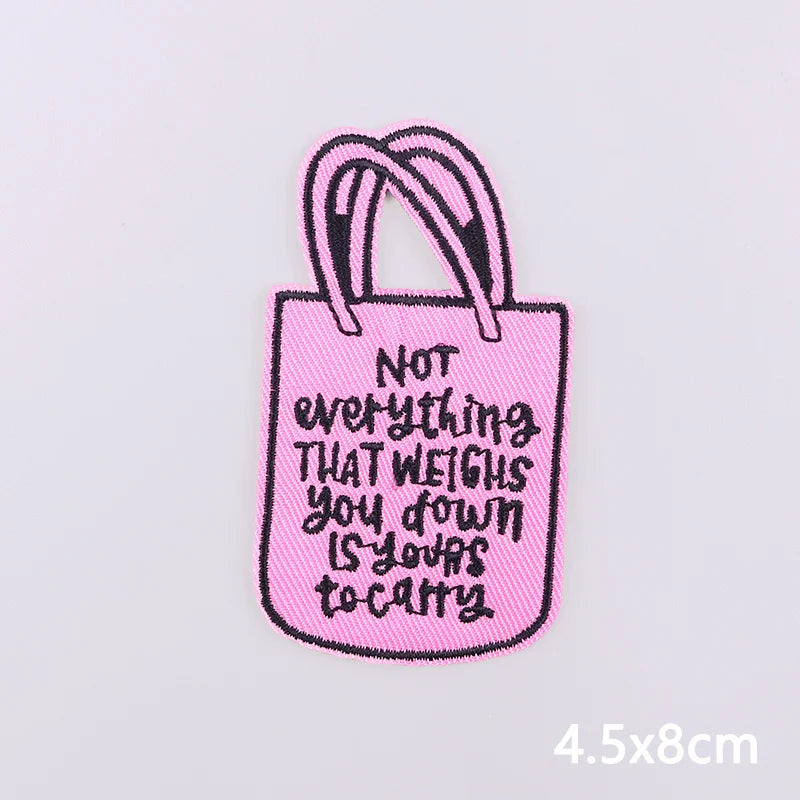 Pink embroidered tote bag featuring black text that reads Not everything that weighs you down is your to carry
