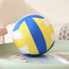 A blue and yellow plush volleyball ball resting on a light green surface.