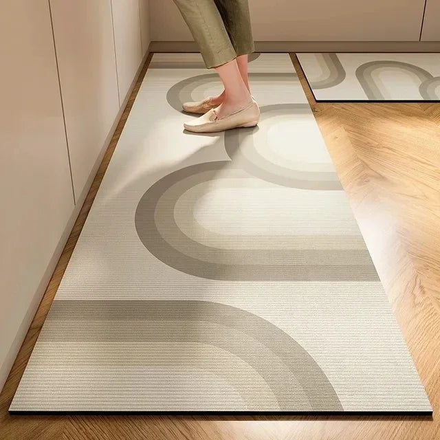 A light beige kitchen floor mat with curved gray patterns placed on a wooden floor.