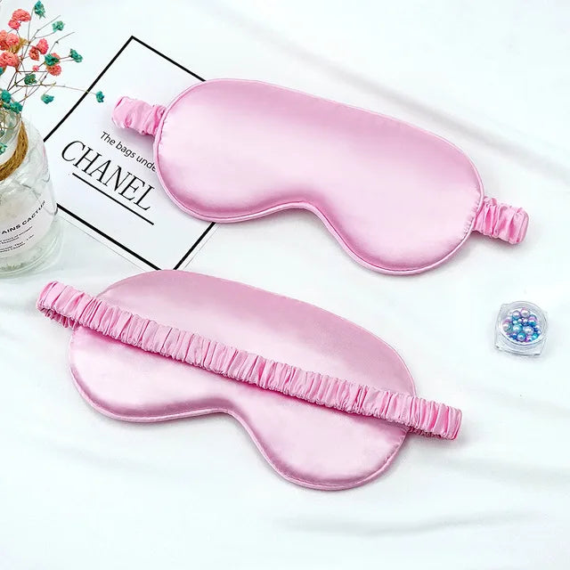 Pink silk sleep mask with ruffled edge displayed on a white background.