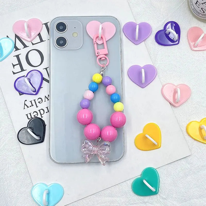 A collection of pink and purple metal heart phone charms and connectors displayed on a white background.