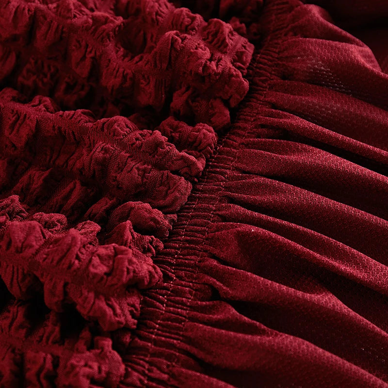 Close-up of a deep red stretch knit sofa cover featuring a textured bubble lattice pattern.