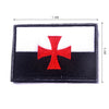 Black and white embroidered patch featuring a red cross on a rectangular fabric background.