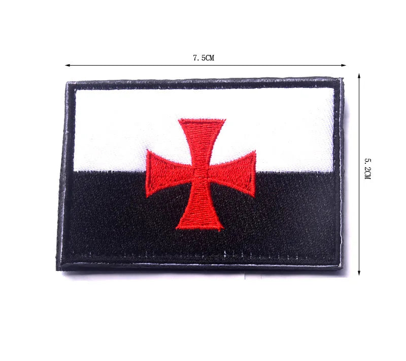 Black and white embroidered patch featuring a red cross on a rectangular fabric background.