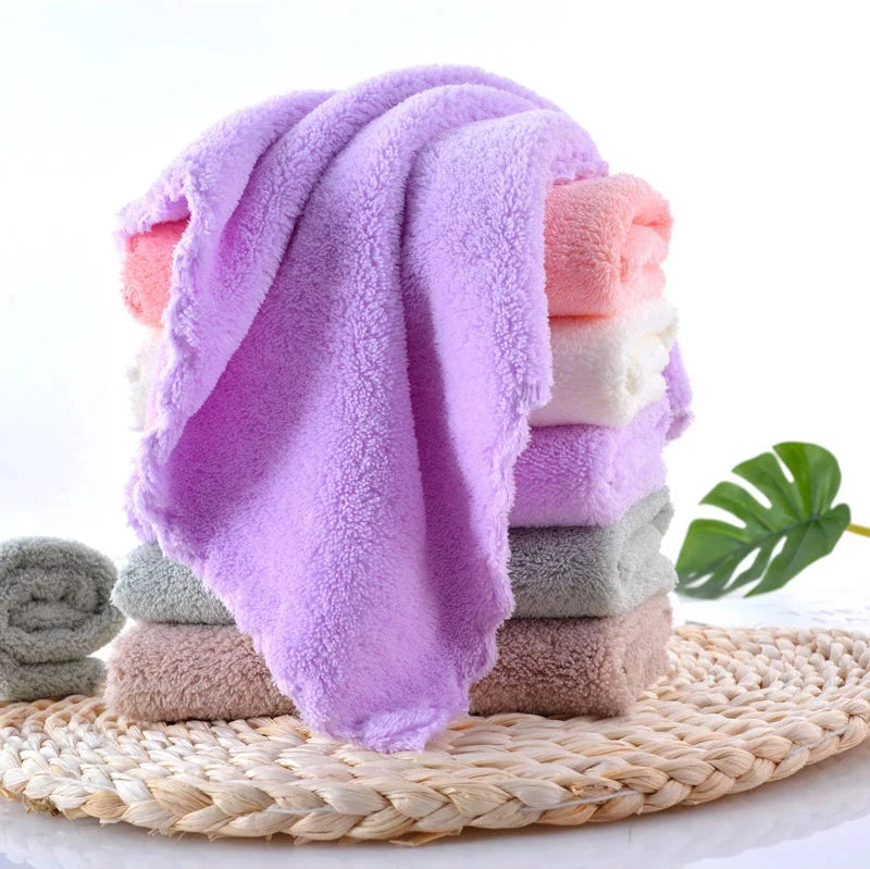 A stack of ten luxury coral velvet cleaning face towels in various shades of pink and peach resting on a woven mat.