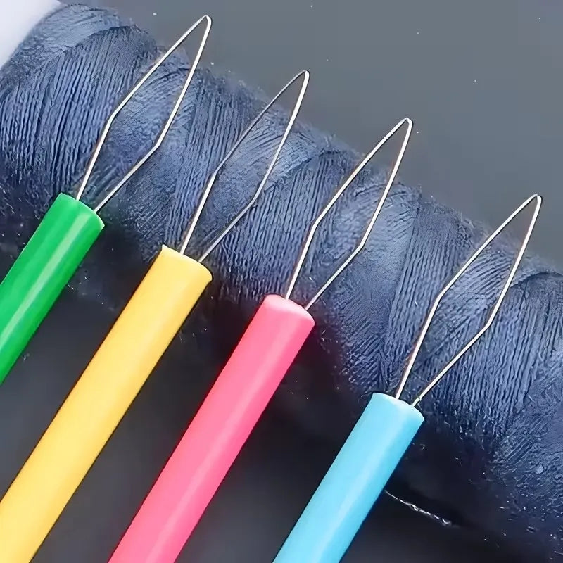 A collection of colorful needle threaders in green, yellow, pink, and blue are shown coiled on a dark fabric.